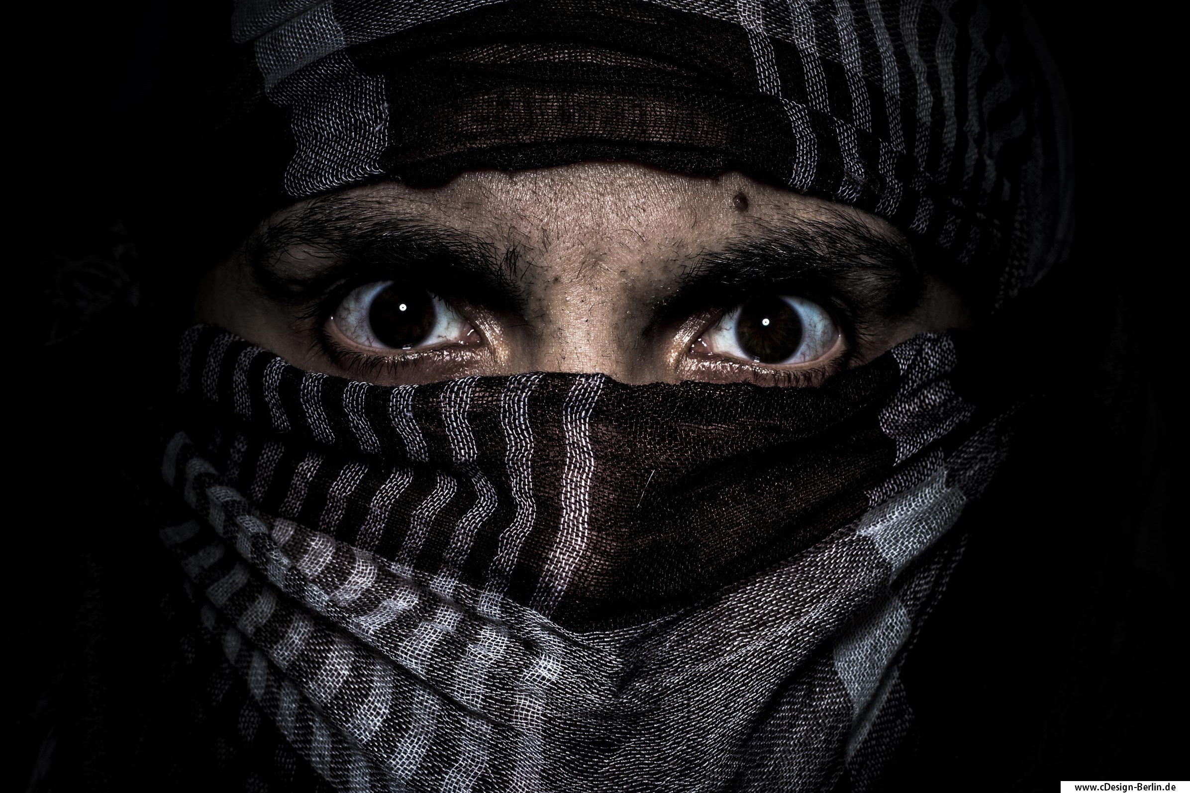 Beurteile einen Menschen nie nach seinem Äußeren, seiner Herkunft oder Religion, denn wir sind alle Teil unserer Erde. Auf diesem Foto trage ich ein dunkles Tuch mit weißen Streifen versehen. Es bedeckt meine Haare und die Hälfte meines Gesichtes, nur die Augen schauen hervor. Mein Blick fest auf die Kamera gerichtet, meine Augen weit geöffnet, ein stummer Schrei. Das Gesamtbildnis ist dunkel und düster gehalten. Der Fokus liegt hauptsächlich auf den Augen, so dass dem Betrachter Raum für eigene Interpretionen bleiben.