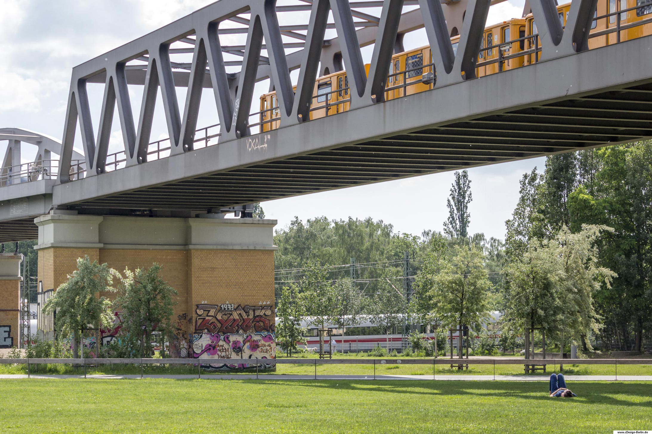  Wenn du dich der Schnelllebigkeit Berlins entziehen möchtest, lege dich doch einfach mal auf eine Wiese. Um dich herum keine Menschenseele, weil sie alle in Eile sind. Nur du bist an diesem Ort, ganz klein und fast unscheinbar auf dieser riesigen Grünfläche. Über dir die Brücke, wo in regelmäßigen Abständen die U-Bahn vorüberzieht. Vor dir ebenfalls vorbeifahrende Züge, dessen Geräusch du als Musik wahrnimmst. Die vielen Bäume und Sträucher untermalen dieses Gesamtbild. Ruhe in dir und finde einen Weg der Entschleunigung. Bezirk: Berlin- Kreuzberg