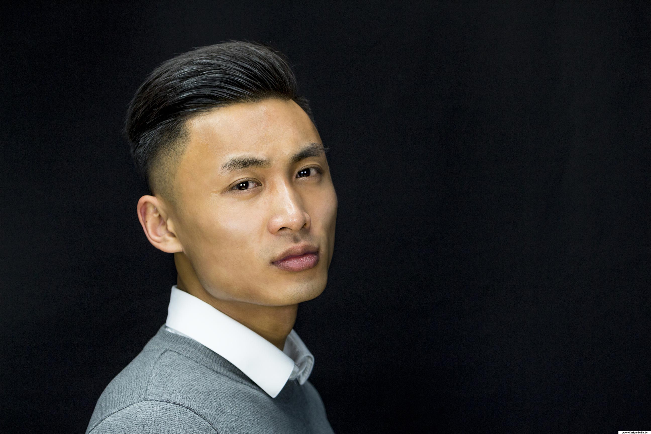 Dieses Foto ist ein klassisches Bewerbungsfoto. Hier habe ich ein jungen vietnamesischen Mann abgelichtet, dessen Gesicht sehr markant und ausdrucksstark zur Geltung kommt. Seine Augen zeigen Willensstärke und Kraft, sein Kopf über die Schulter blickend. Er trägt einen grauen Pullover und darunter ein weißes Hemd.