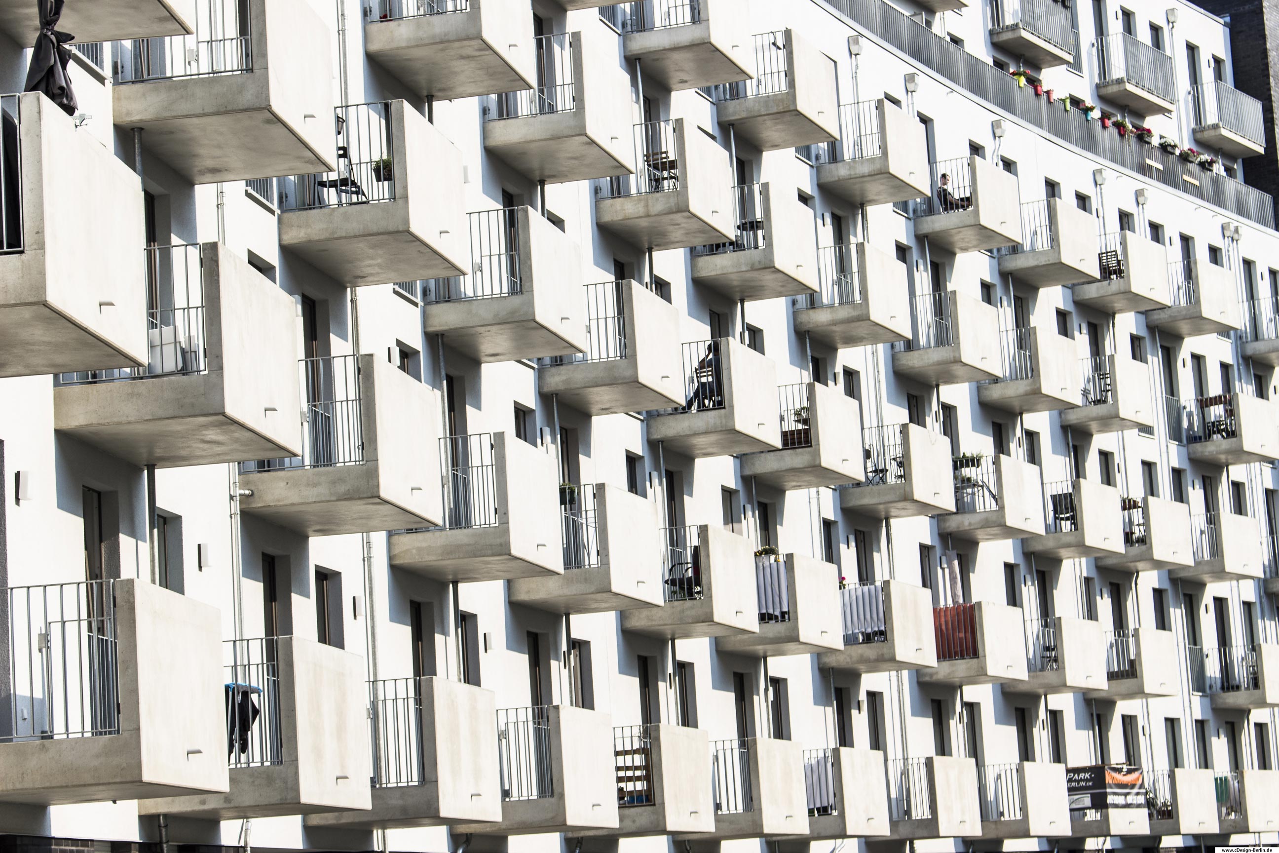 Stell dir vor du bist nicht allein, teilst dein Dasein mit vielen hundert anderen Menschen. Für mich ein wirklich bizares Bild auf dem Hinterhof eines Wohnhauses mitten in Berlin. In diesem Haus wohnen die Menschen von außen betrachtet auf engem Raum, Nase an Nase. Über und unter ihnen eine körperlänge Entfernung vom Nachbarn. Ein Balkon nach dem anderen aufgereiht, sein gegenüber zum Greifen nah. Die Fassade grau, kaum farbige Akzente. Ein Balkon hat einen roten Sichtschutz, der das Gesamtbild ein wenig lebendiger wirken lässt. Suchst du Leben oder Farben in Form von Bepflanzung oder anderen Details an diesem Ort, muss man wahrscheinlich in den Wohnungen selbst suchen.
