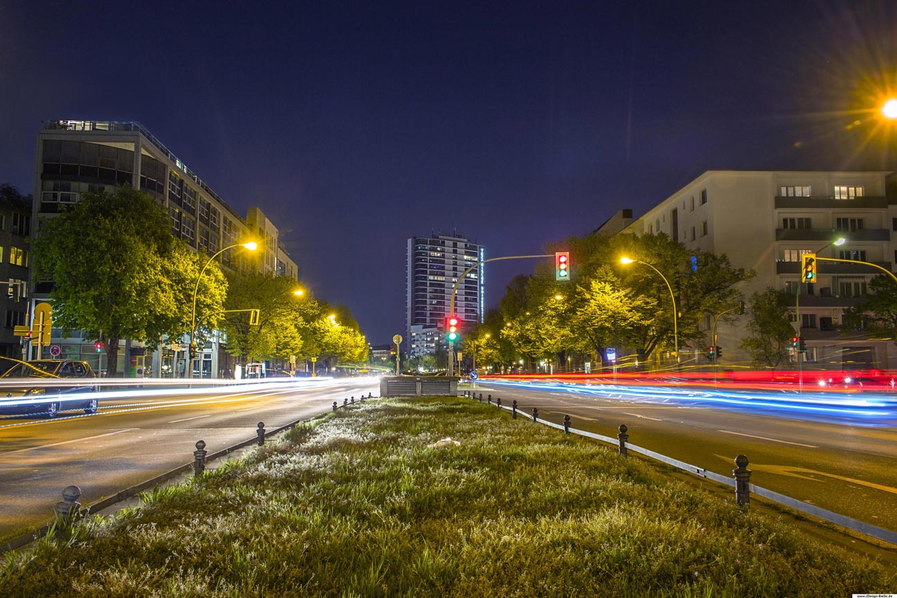Großstädte sind für ihre belebten Straßen bekannt und immer wieder gern ein Motiv für Fotografen. Wie Bienen schwärmen sie aus und bewegen sich von A nach B. Es ist dunkel geworden, die Nacht bricht herein, Straßenlaternen erhellen die Bürgersteige. Auf diesem Foto habe ich mich auf einen Mittelstreifen gestellt, rechts und links von mir die Straße, Wohnblocks und am Horizont mittig ein Gebäude der Telekom zu sehen. Der Fluchtpunkt auf diesem Foto ist zentriert, Straßen und Häuser verlaufen in diesen. Durch die Langzeitbelichtung sind die Autos nicht mehr erkennbar, alles was von ihnen übrig bleibt ist ein Schweif aus roten und blauen Farben.