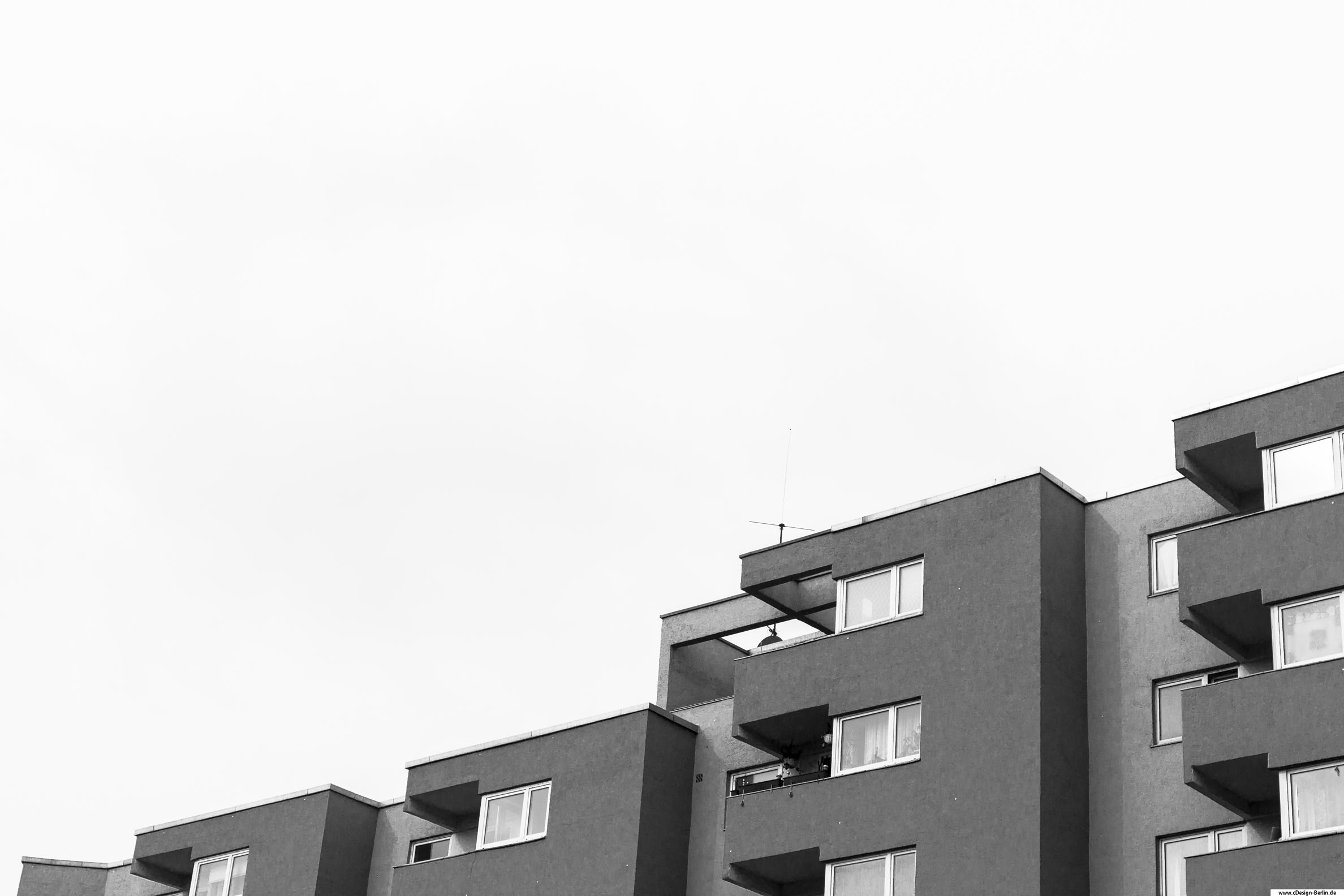 Grau wie eine Maus ist dieses Haus.Auf diesem Foto ist ein Wohnblock dargestellt, der von rechts nach links abfallend wird.
                                        Der rechte Bereich hat drei Balkone, der mittige zwei, dann einen und am Ende des Hauses ist nur noch ein Fenster mit abschliessendem Dach zu sehen.Ein drittel des Fotos besteht aus Himmel und ist in schwarz/ weiß gehalten.